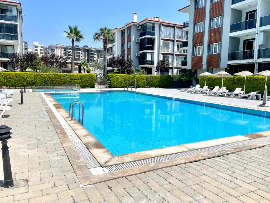 a large blue swimming pool in a apartment complex at Theos Holiday Apartments Room 23 Family Suit Accommodation For Families Only in Kuşadası