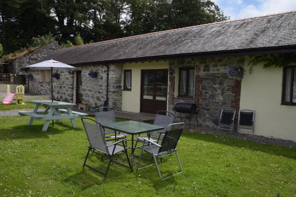 a picnic table and chairs in front of a cottage at Cae Berllan Cottages in Groeslon