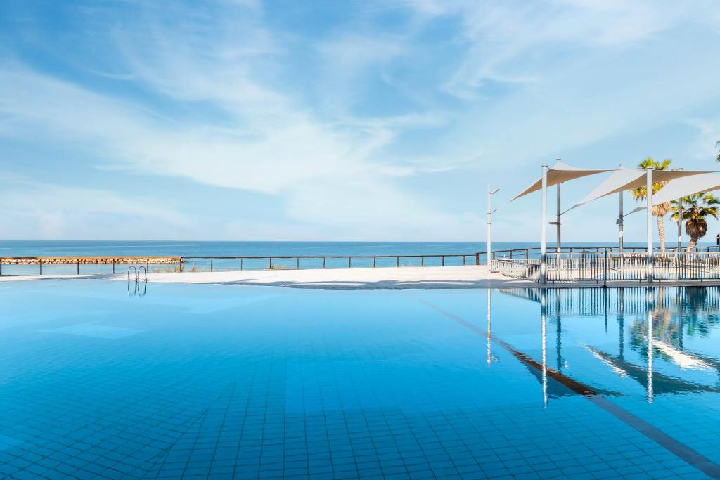 a swimming pool with a view of the ocean at Daniel Herzliya Hotel in Herzelia 