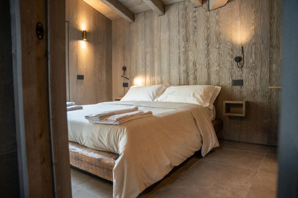 een slaapkamer met een groot bed met witte lakens en kussens bij Le Suites de San Campel RTA in Ponte di Legno