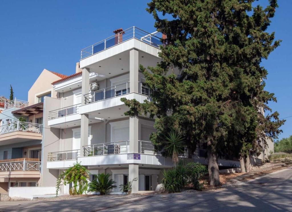 un edificio de apartamentos blanco con un árbol delante en Unique, elegant Bourtzi View Villa en Nauplia