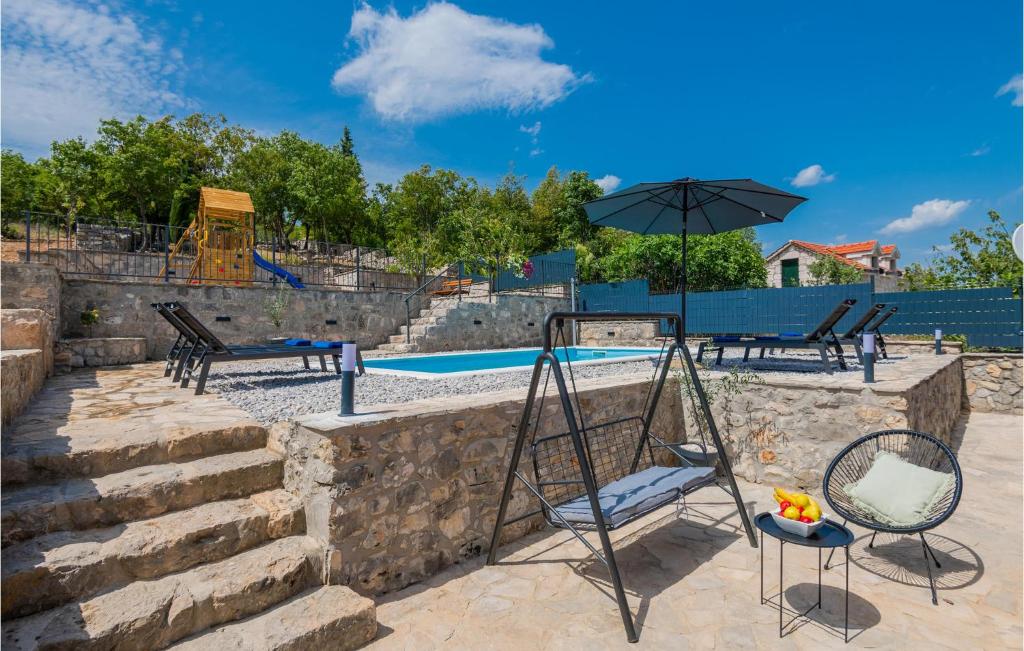 um pátio com cadeiras e um guarda-sol ao lado de uma piscina em Nice Home In Zmijavci With Outdoor Swimming Pool em Zmijavci