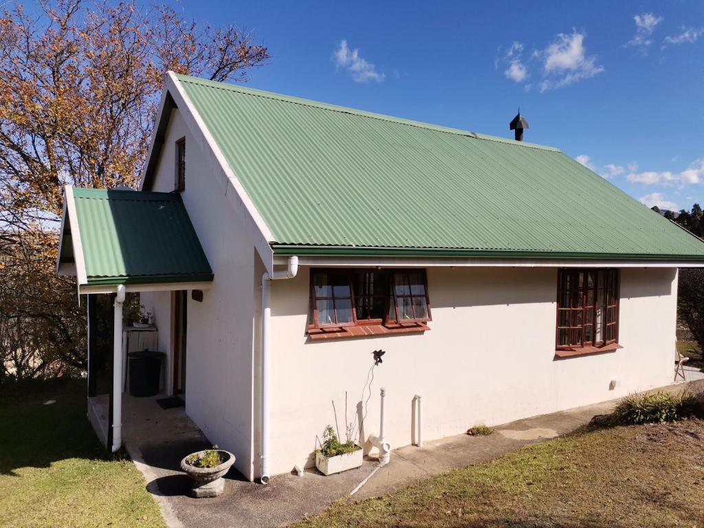 a white house with a green roof at Eagles' Rock in Underberg