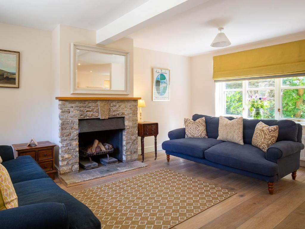 a living room with blue couches and a fireplace at Woodland Cottage in Temple Guiting
