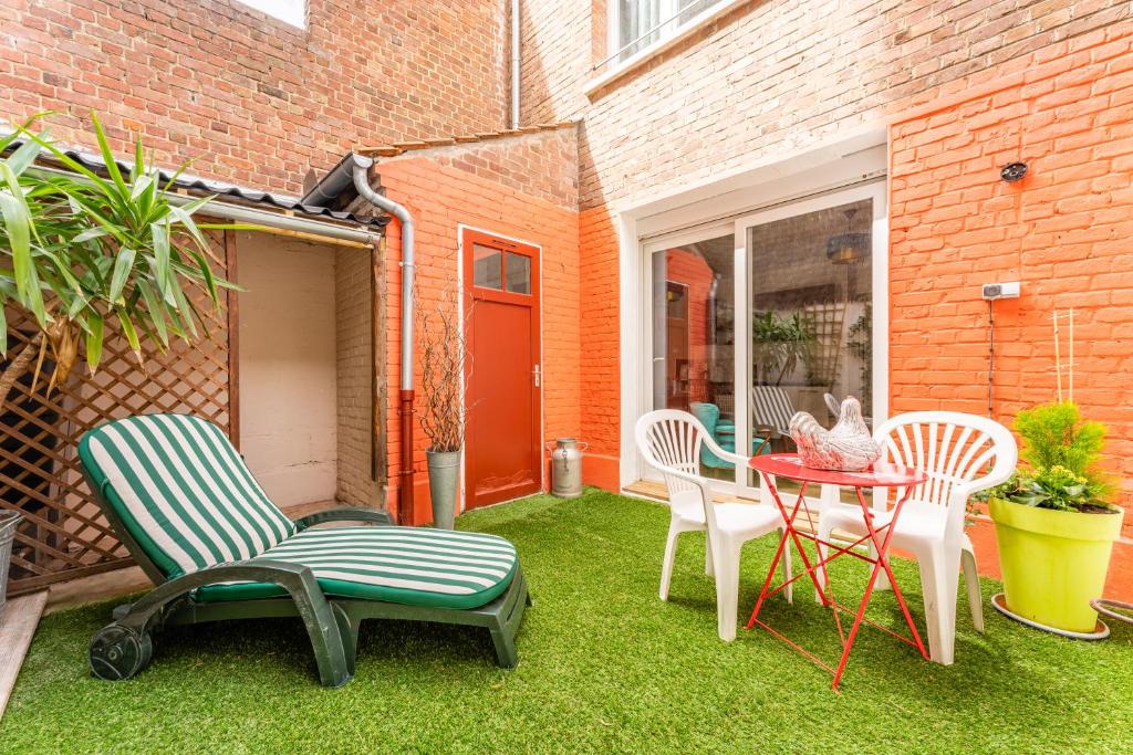 a patio with chairs and a table on the grass at Les Potiers RdC - proche centre historique in Arras