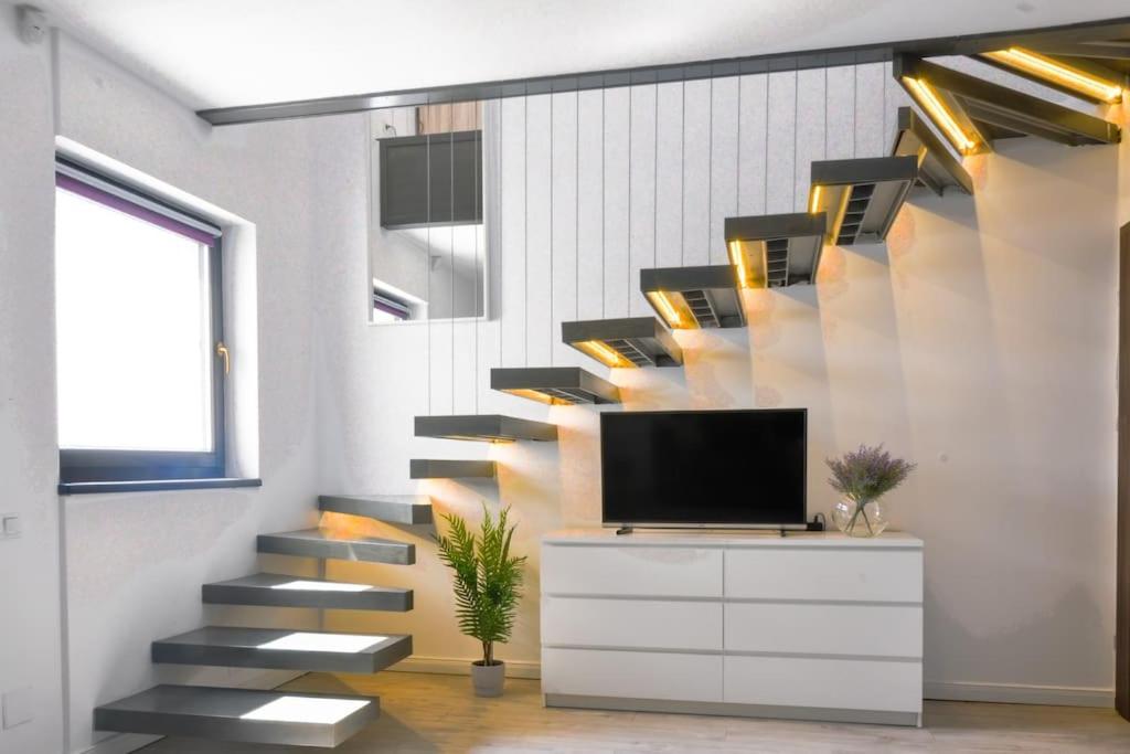 a living room with a staircase with a tv and a tv stand at Ultracentral modern apartment in Târgu-Mureş
