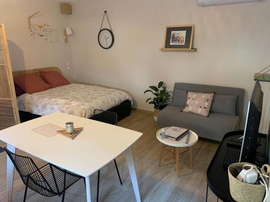 ein kleines Wohnzimmer mit einem Bett und einem Tisch in der Unterkunft Charmant studio 