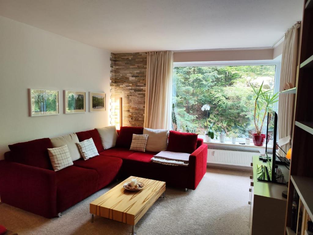 a living room with a red couch and a table at Apartement Wald-Panorama Fuchsenstein in Spiegelau