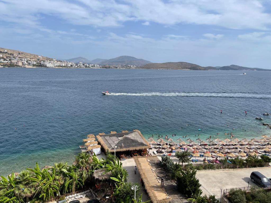 een strand met parasols en een boot in het water bij Port Side Sarande in Sarandë