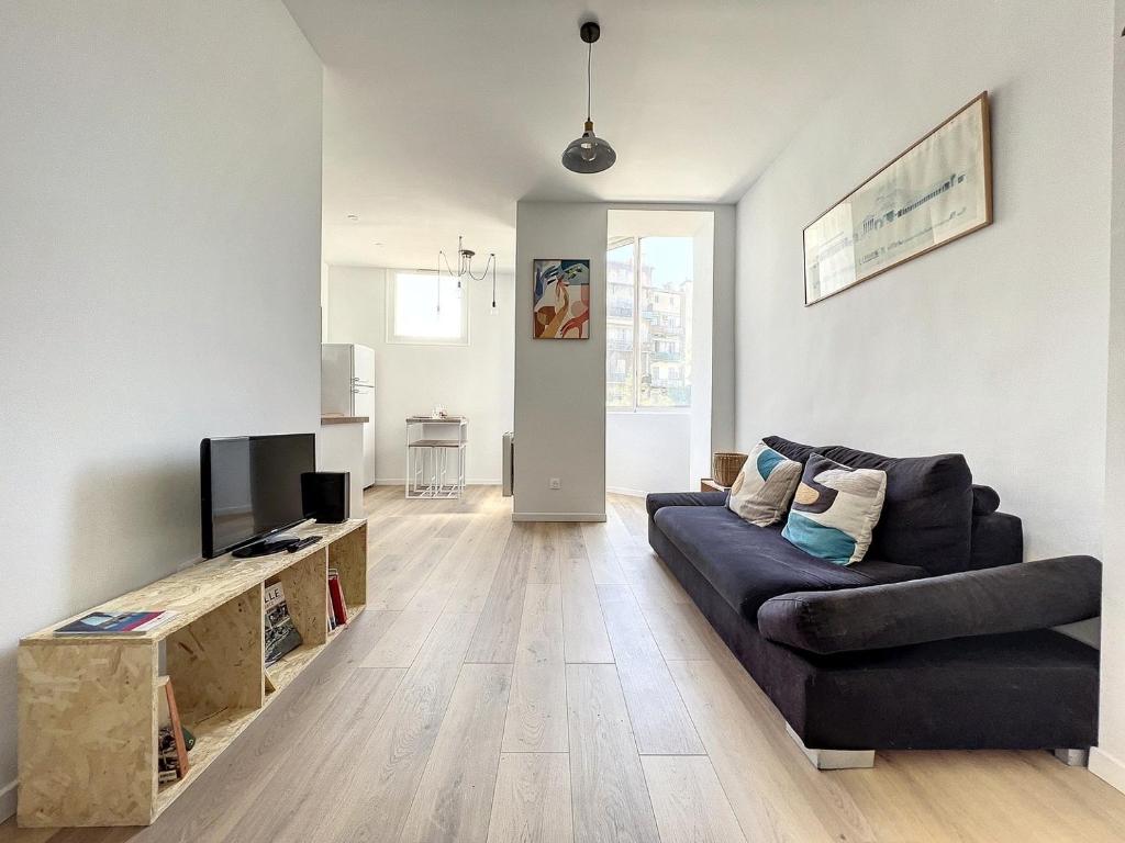 a living room with a couch and a tv at Charmant appartement rénové - Central & Spacieux - Les Frères de la Loc' in Marseille