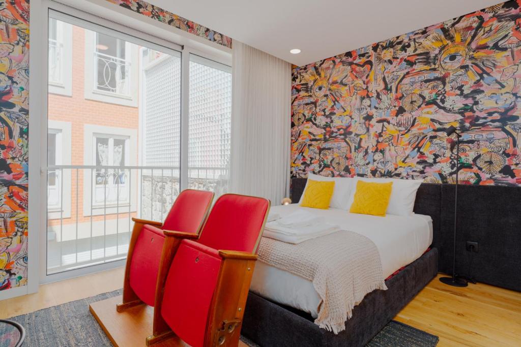 een slaapkamer met een bed en twee rode stoelen bij Theater Studio in Porto