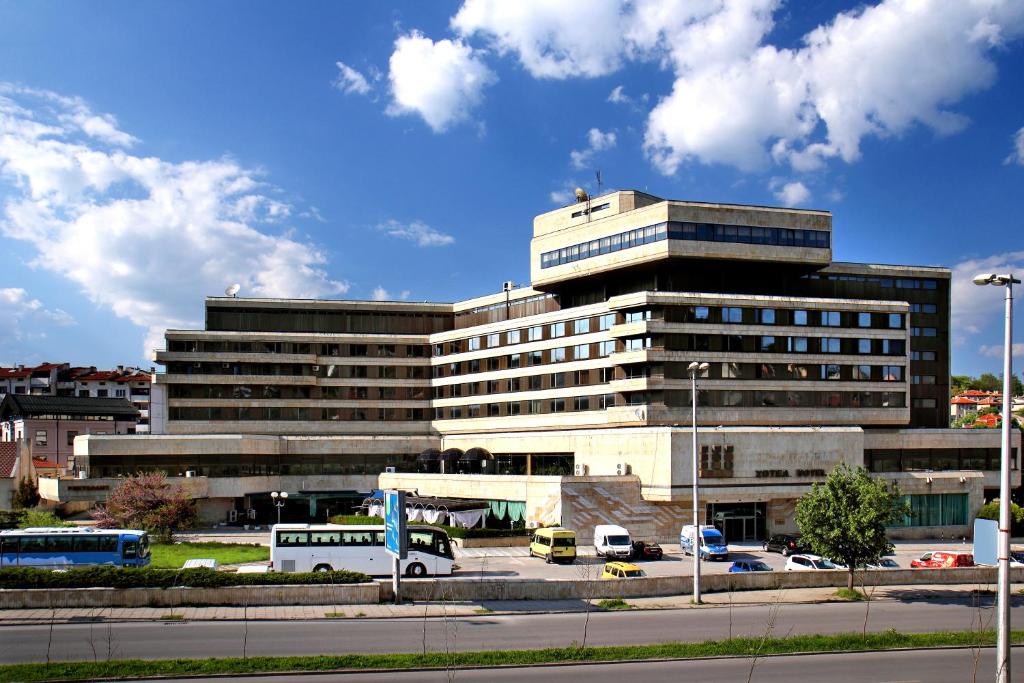 a large building with cars parked in a parking lot at Grand Hotel Shumen in Shumen