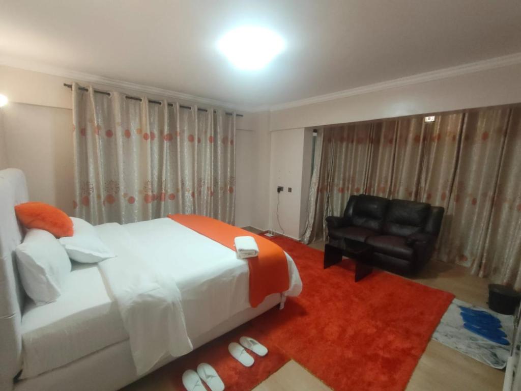 a bedroom with a bed and a chair and a couch at Zerra Luxury 3 bedroom in Nakuru CBD in Nakuru