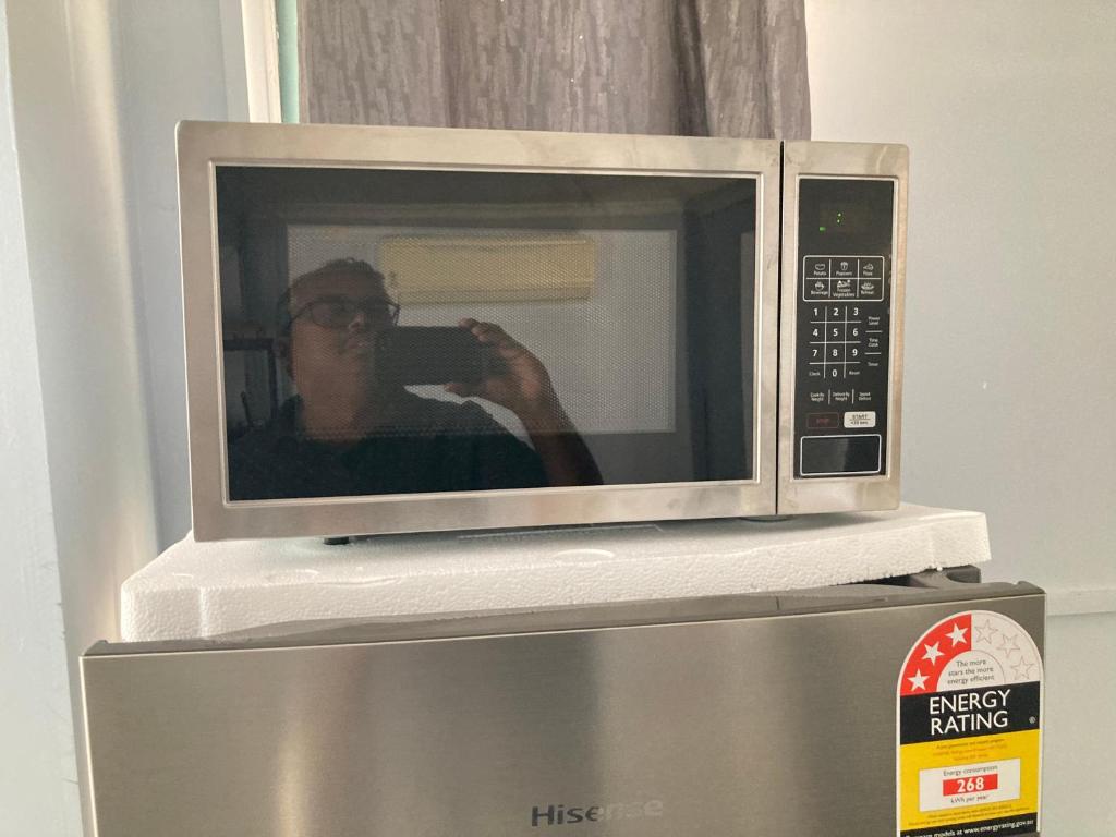 a person taking a picture of a microwave at Stunning Darwin City Studio in Darwin