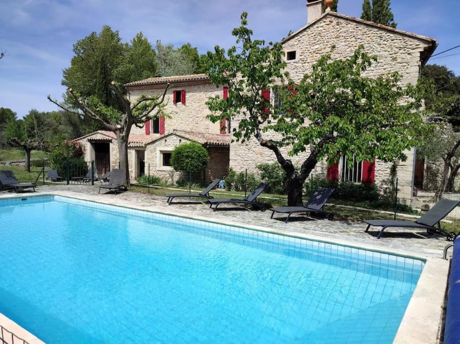 une grande piscine devant un immeuble dans l'établissement Ancien Moulin Drôme Provençale, à Montbrison-sur-Lez