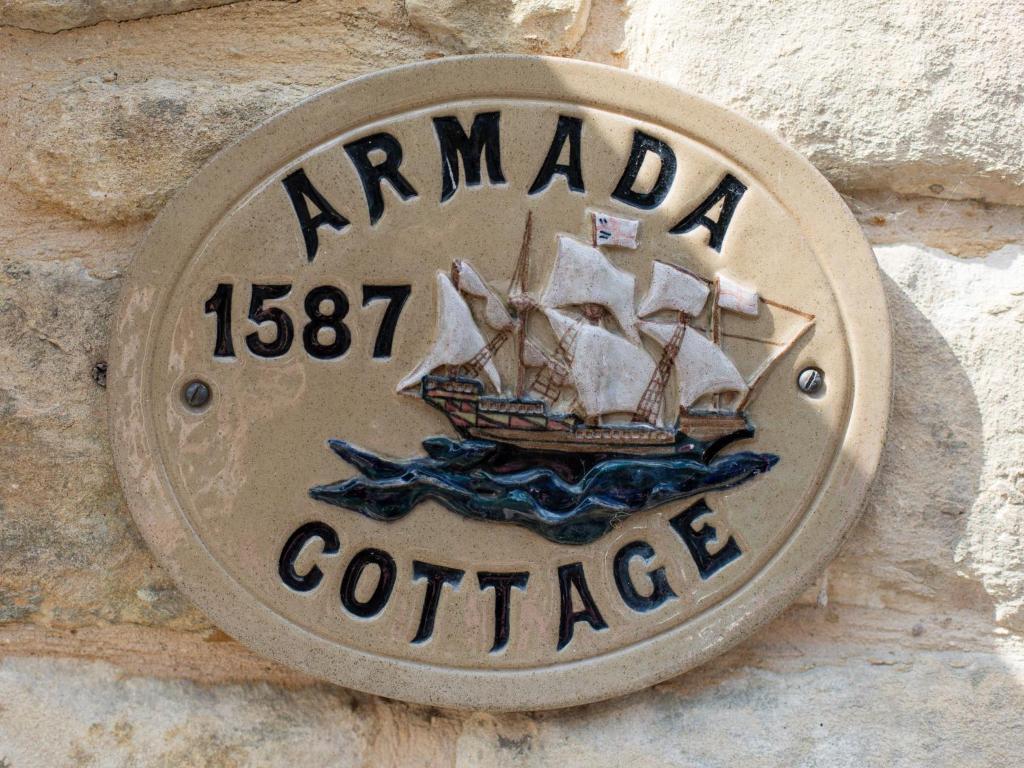 a sign on a stone wall with a ship on it at Armada Cottage in Charlbury