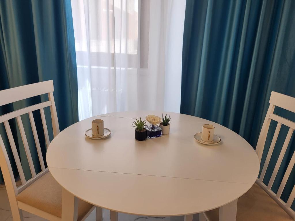 a white table with two cups and plants on it at Savoy Mamaia Studio in Mamaia