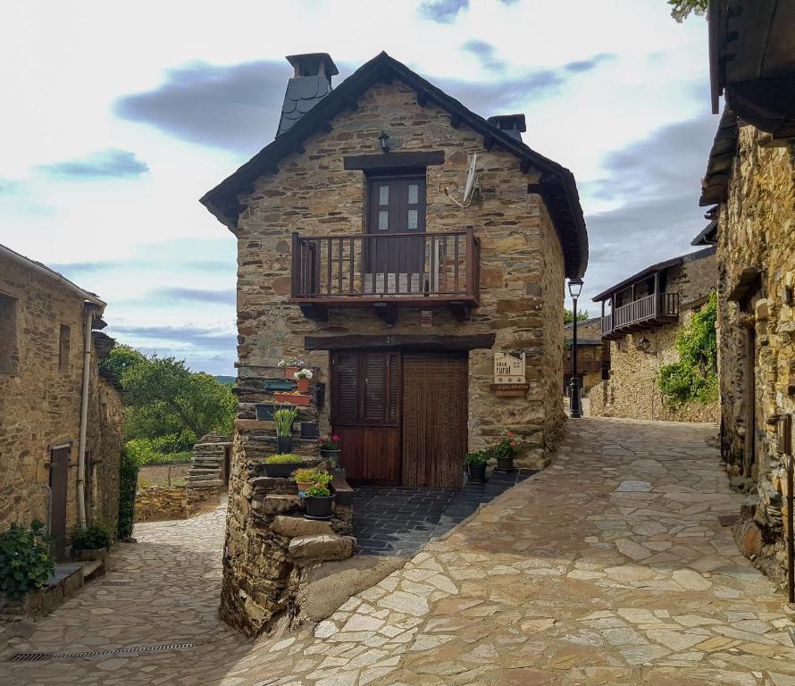 Casa de piedra antigua con balcón en una calle en Casa rural Rosita, en Santa Cruz de los Cuérragos