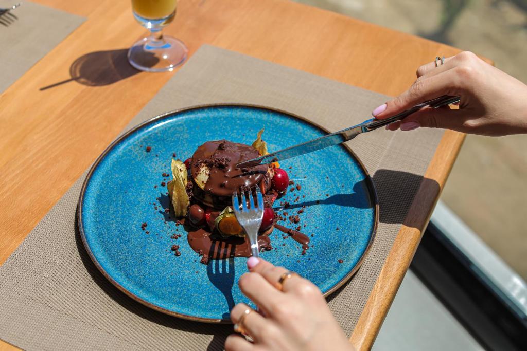 a person eating a piece of chocolate dessert on a blue plate at Black Diamond Hotel Dhermi in Dhërmi