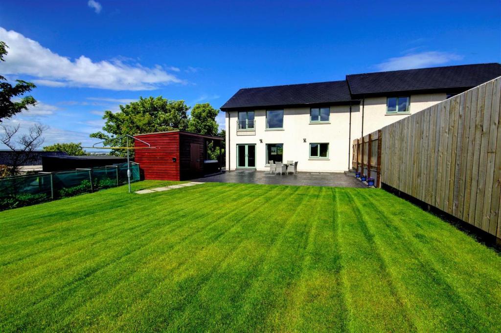 a large lawn in front of a white house at Aurora - Self Catering, Kirkwall, Quiet Location with Luxury Hot Tub in Orkney