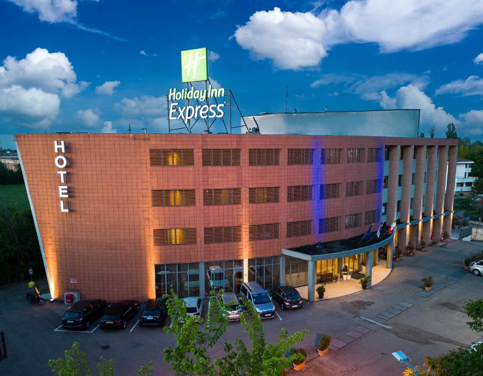 un bâtiment d'hôtel avec des voitures garées dans un parking dans l'établissement Holiday Inn Express Parma, an IHG Hotel, à Parme