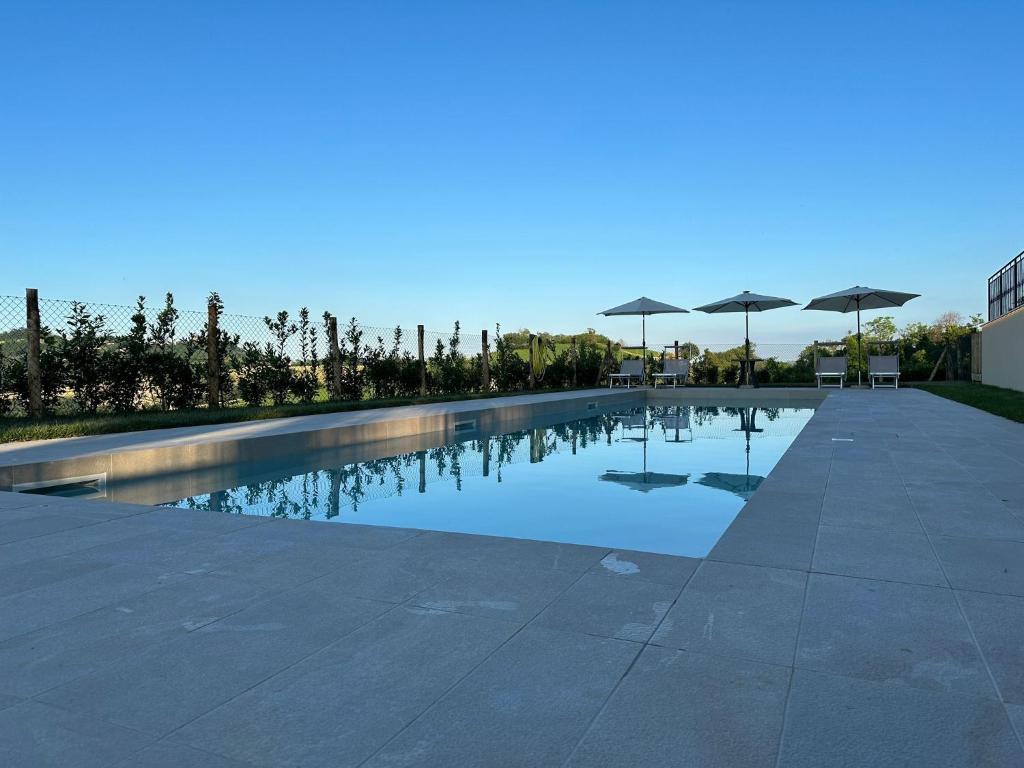 a swimming pool with umbrellas in the middle at Villa lussuosa con piscina e giardino 350m2 in Montottone