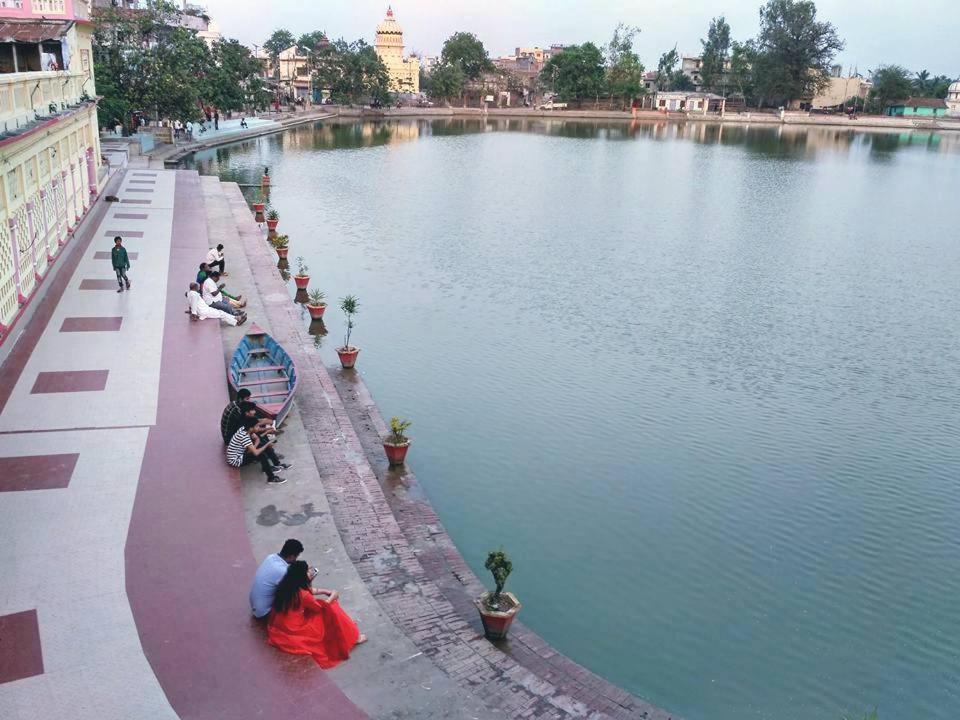 un grupo de personas sentadas junto a un cuerpo de agua en Mithila Culture Homestay Janak Kuti, en Janakpur