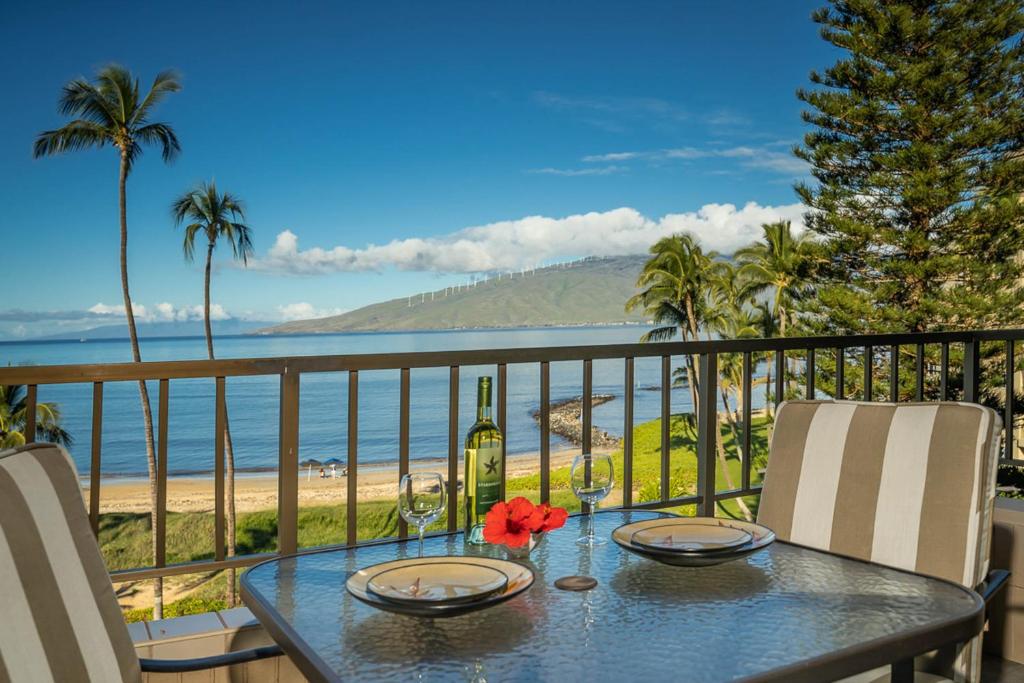 a table with a bottle of wine on a balcony overlooking the beach at Koa Lagoon 506 in Kihei