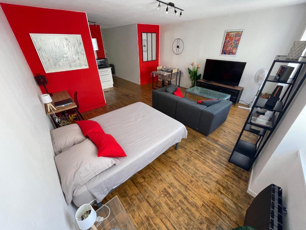 a living room with a white bed and a red wall at En Salvy : hyper centre + parking gratuit in Albi
