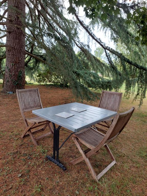 uma mesa e duas cadeiras sentadas ao lado de uma árvore em La Cressonnière 56 em Missiriac
