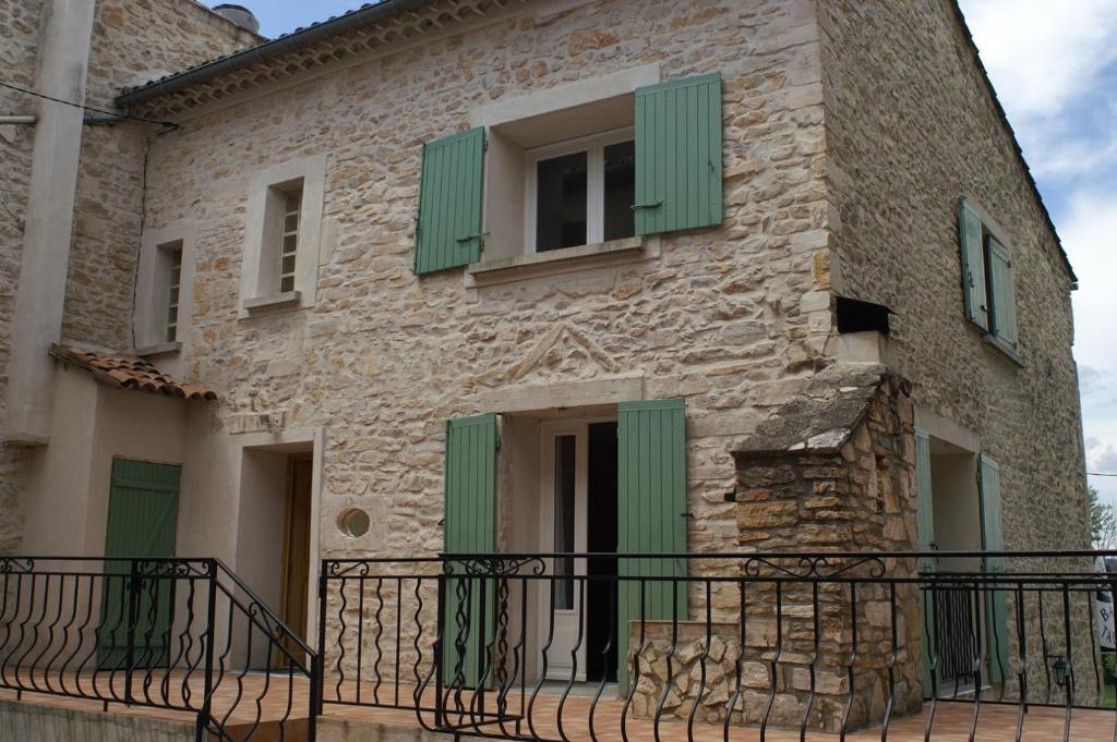 Saint-Jean-de-Maruéjols-et-AvéjanにあるLou Quinsouの石造りの家(緑のシャッター、バルコニー付)