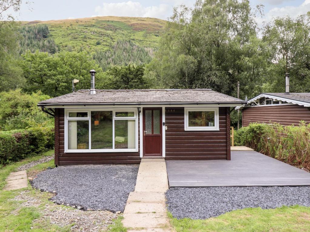 a small cabin with a porch and a deck at Chalet 2 in Machynlleth