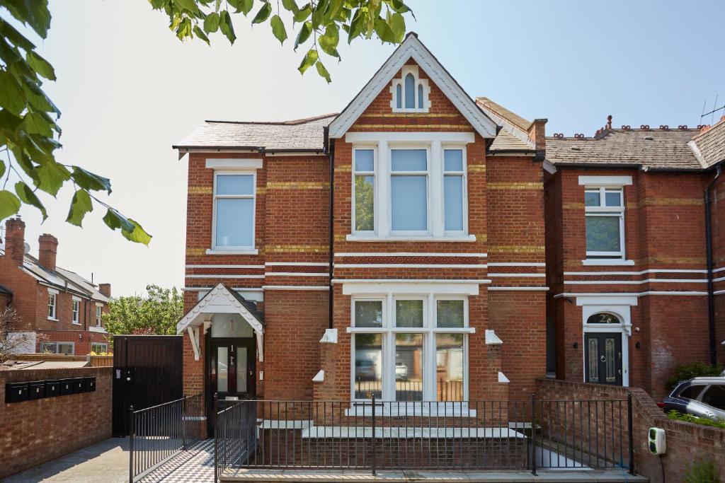 a red brick house with a black fence at Ealing Broadway by Viridian Apartments in Ealing