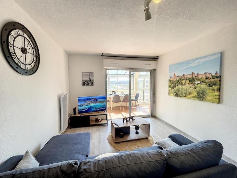 un salon avec un canapé et une horloge au mur dans l'établissement Le Panoramique - Sublime vue sur la Cité, à Carcassonne