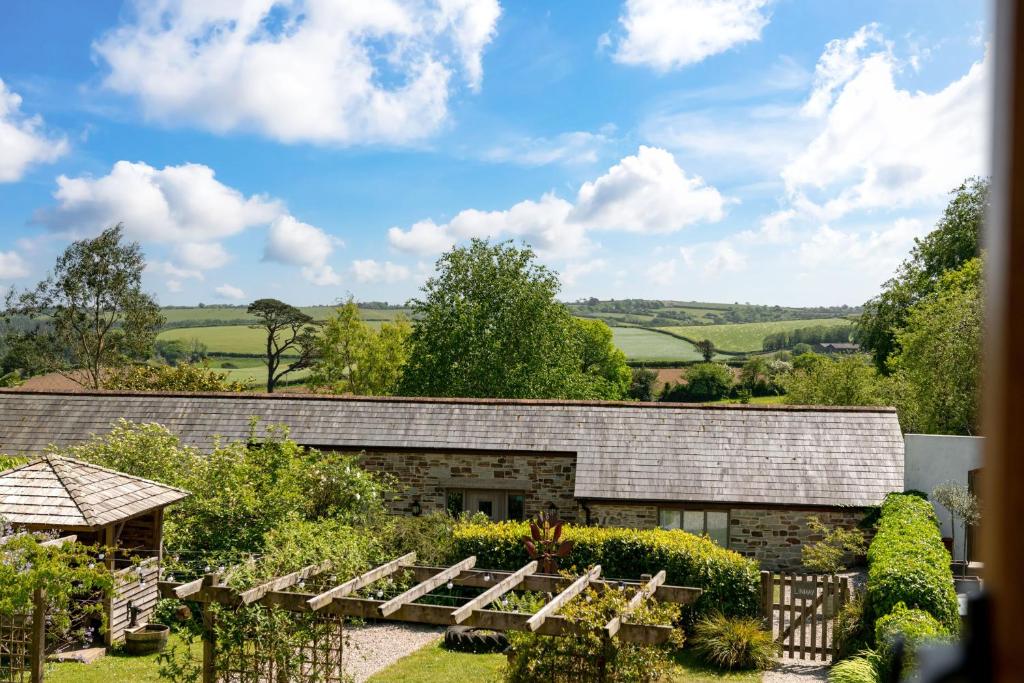 a view of a garden with a stone building at Linhay at East Trenean Farm -Luxury retreat for 2 with stunning rural views, private hot tub and EV charging in Looe