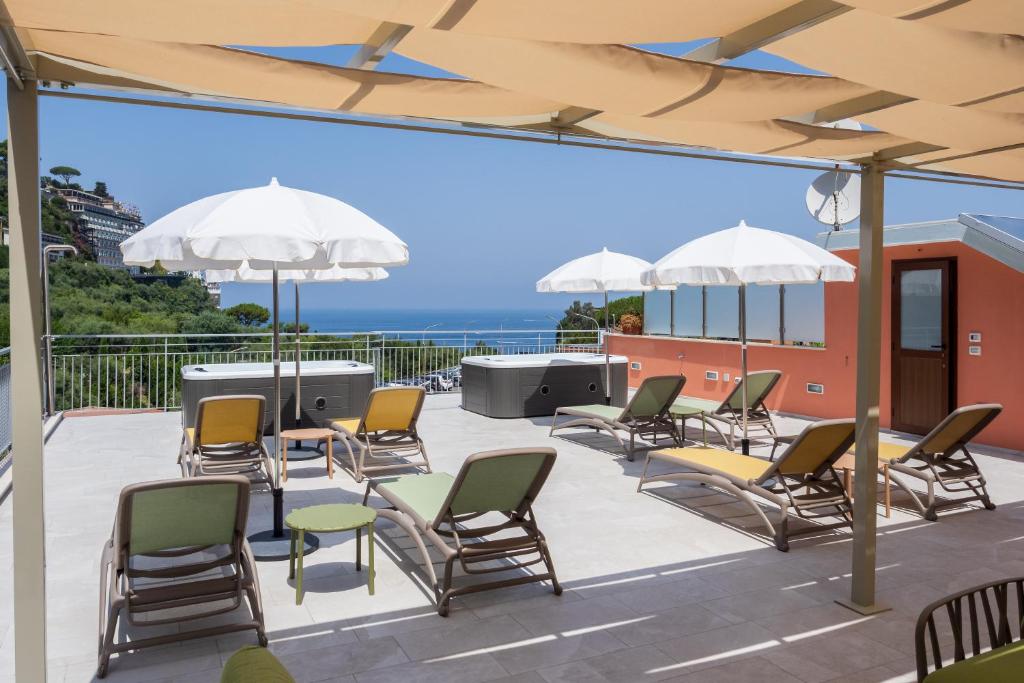 een patio met stoelen, tafels en parasols bij FUTURA SMART Flat Sorrento in Sorrento