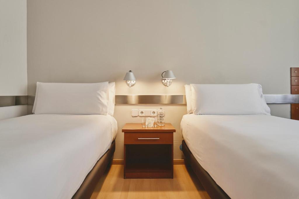 two beds sitting next to each other in a room at Tres Torres Atiram Hotels in Barcelona