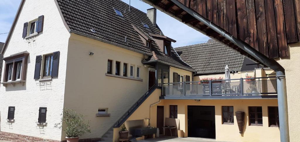 un edificio blanco con balcón y una casa en Les Hirondelles du MAMBOURG, en Sigolsheim