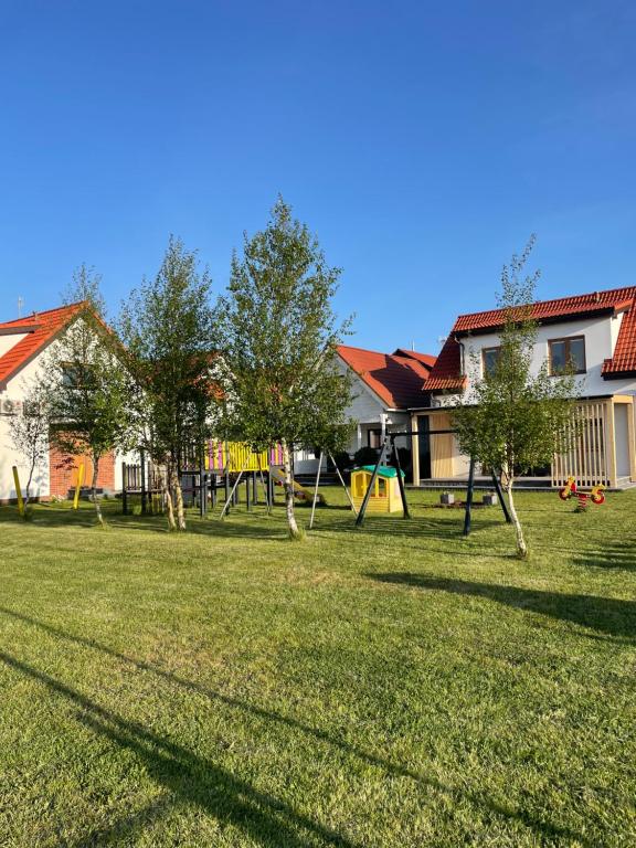 un patio con un parque infantil con árboles y una casa en Morski Zakątek Apartamenty, en Rowy