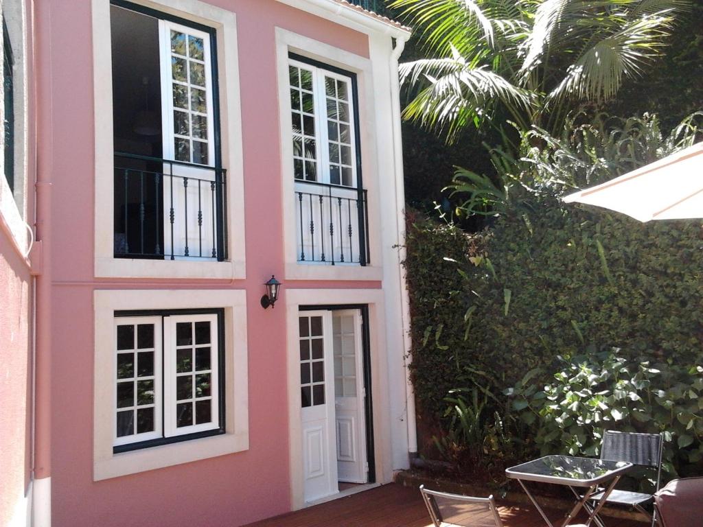 a pink house with a white door and a table at Casa do Arco in Sintra