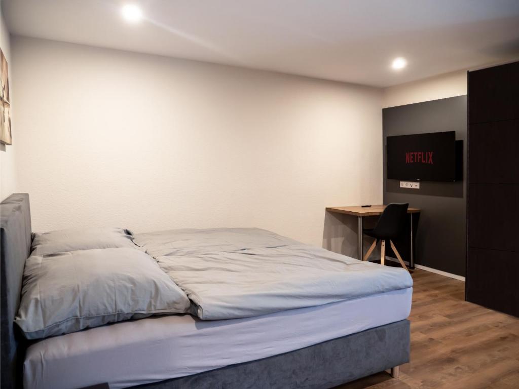1 dormitorio con 1 cama y escritorio con TV en Pension HSL en Graben-Neudorf