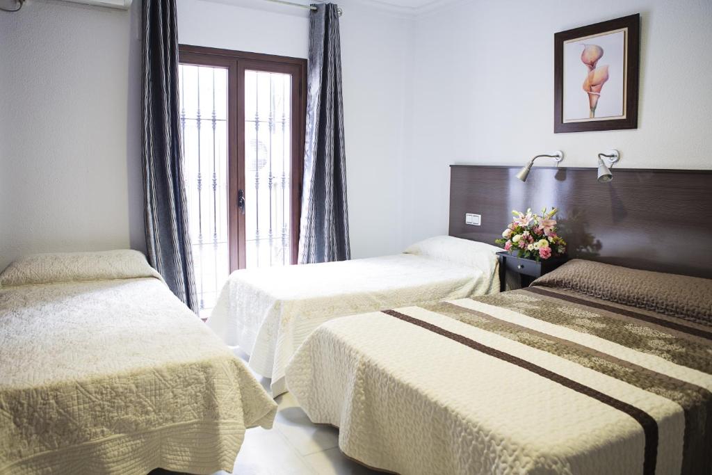 a hotel room with two beds and a window at La Casa de los Faroles in Córdoba