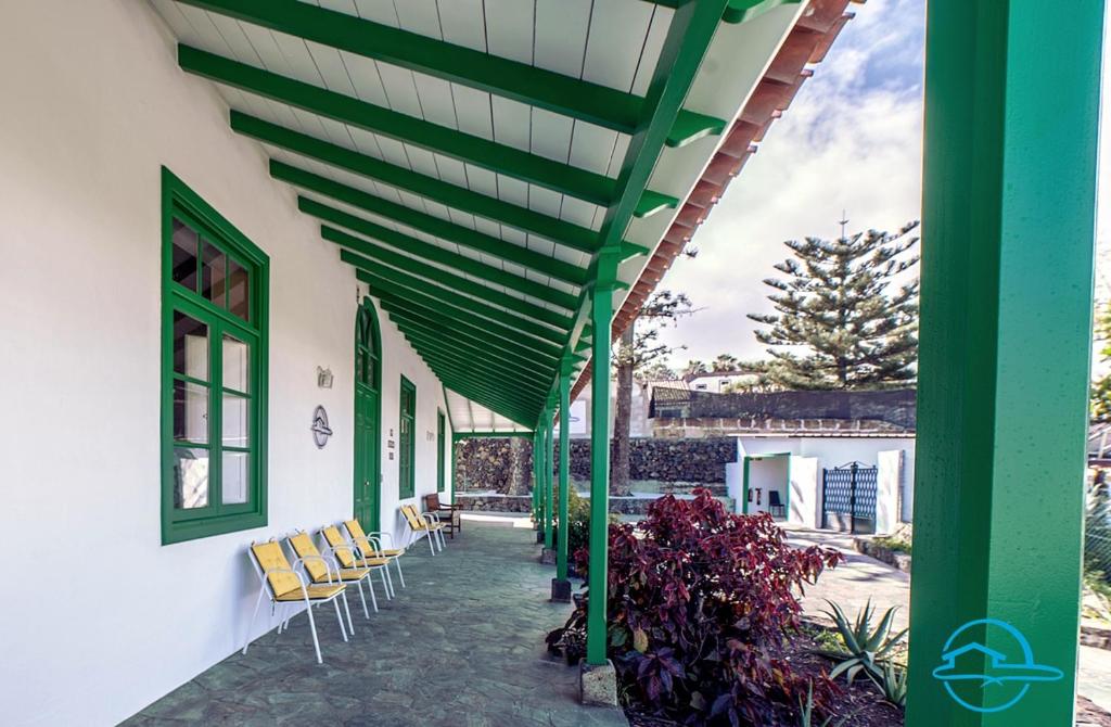 pérgola verde en un edificio con sillas y plantas en La Violeta Home en Puerto de la Cruz