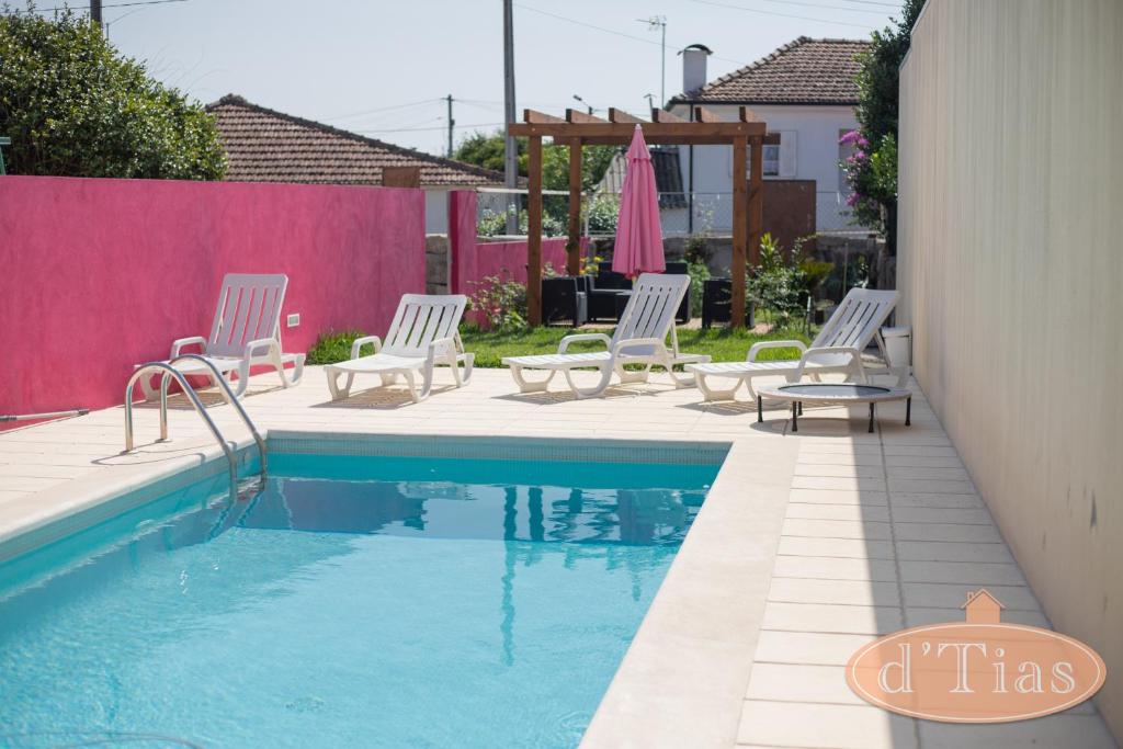 a pool with white chairs and a pink fence at Casa das Tias in Baltar