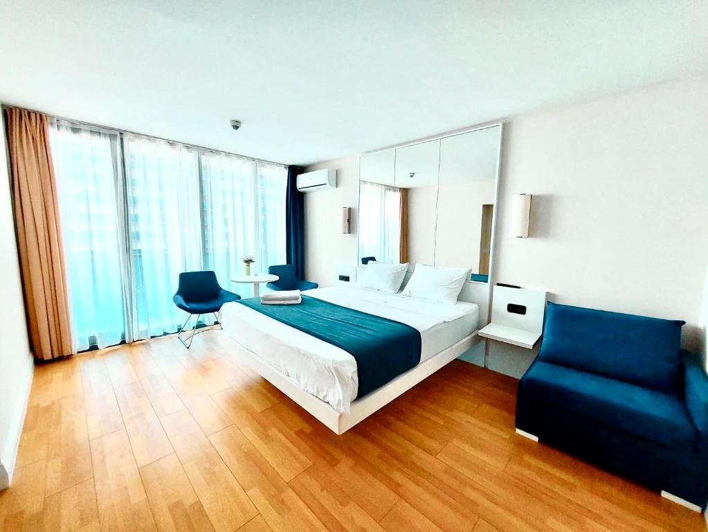 1 dormitorio con 1 cama grande y 1 silla azul en Orbi City Sea View, en Batumi