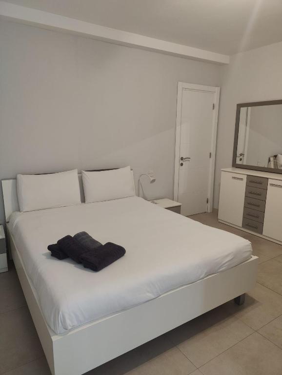 - une chambre avec un lit blanc et une serviette noire dans l'établissement Gżira, 2 bedroom apartment, à Il-Gżira