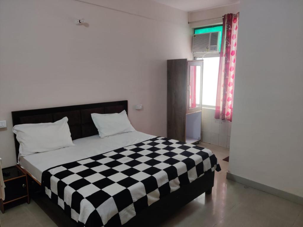 a bedroom with a black and white checkered bed at Apna Guest House Dehradun in Dehradun