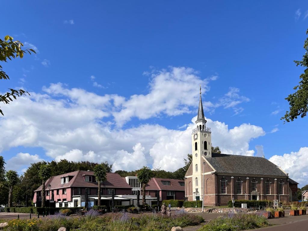 una iglesia con un campanario en la parte superior de un edificio en Hotel De Oringer Marke & Stee by Flow, en Odoorn