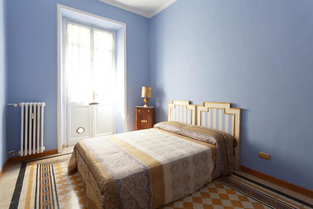 een slaapkamer met een bed met blauwe muren en een raam bij Vanchiglia Apartment - Torino in Turijn