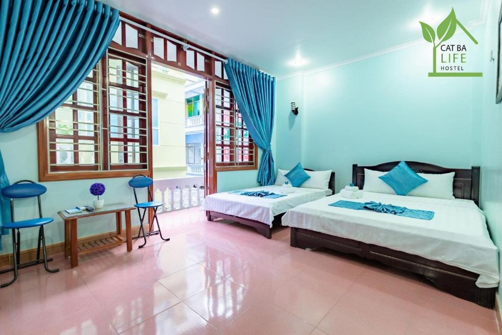 2 camas en una habitación con paredes y ventanas azules en Cat Ba Life Hostel en Hai Phong